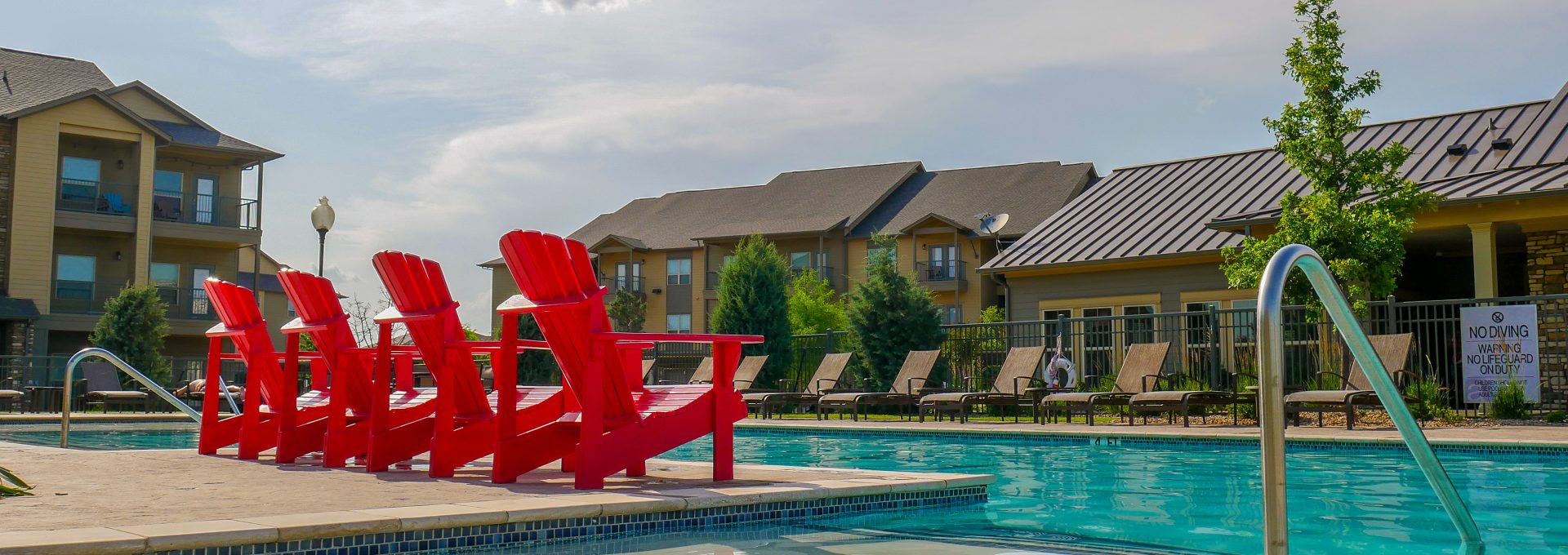 a pool with red chairs and a red umbrella at The Anatole on MacArthur North
