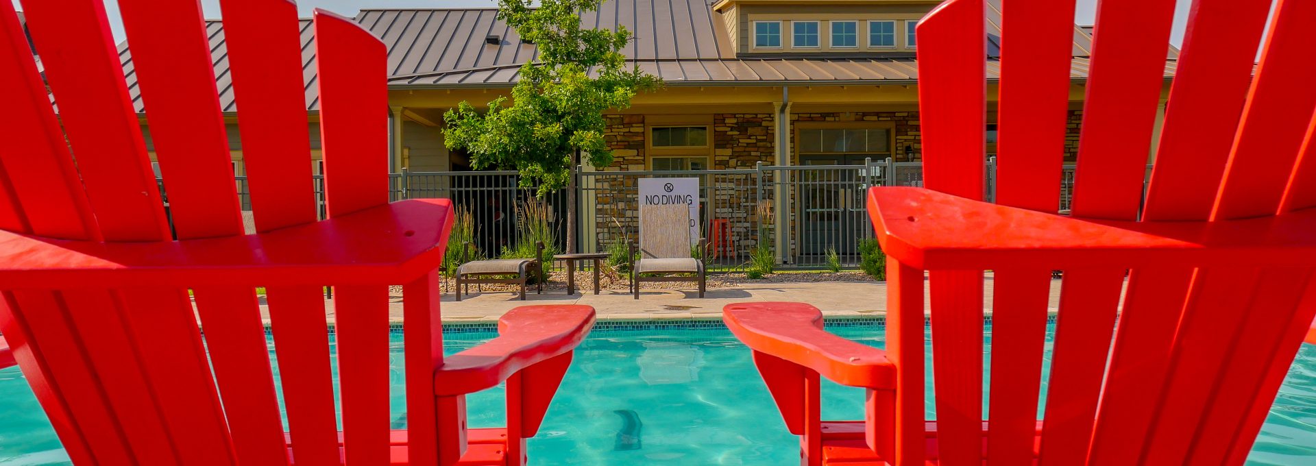two red chairs by a pool with a building in the background at The Anatole on MacArthur North