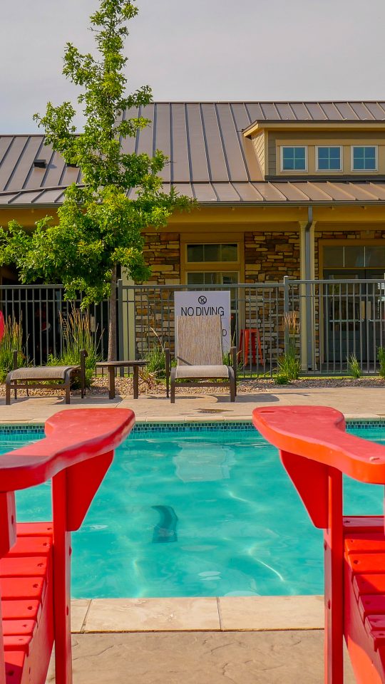 two red chairs by a pool with a building in the background at The Anatole on MacArthur North